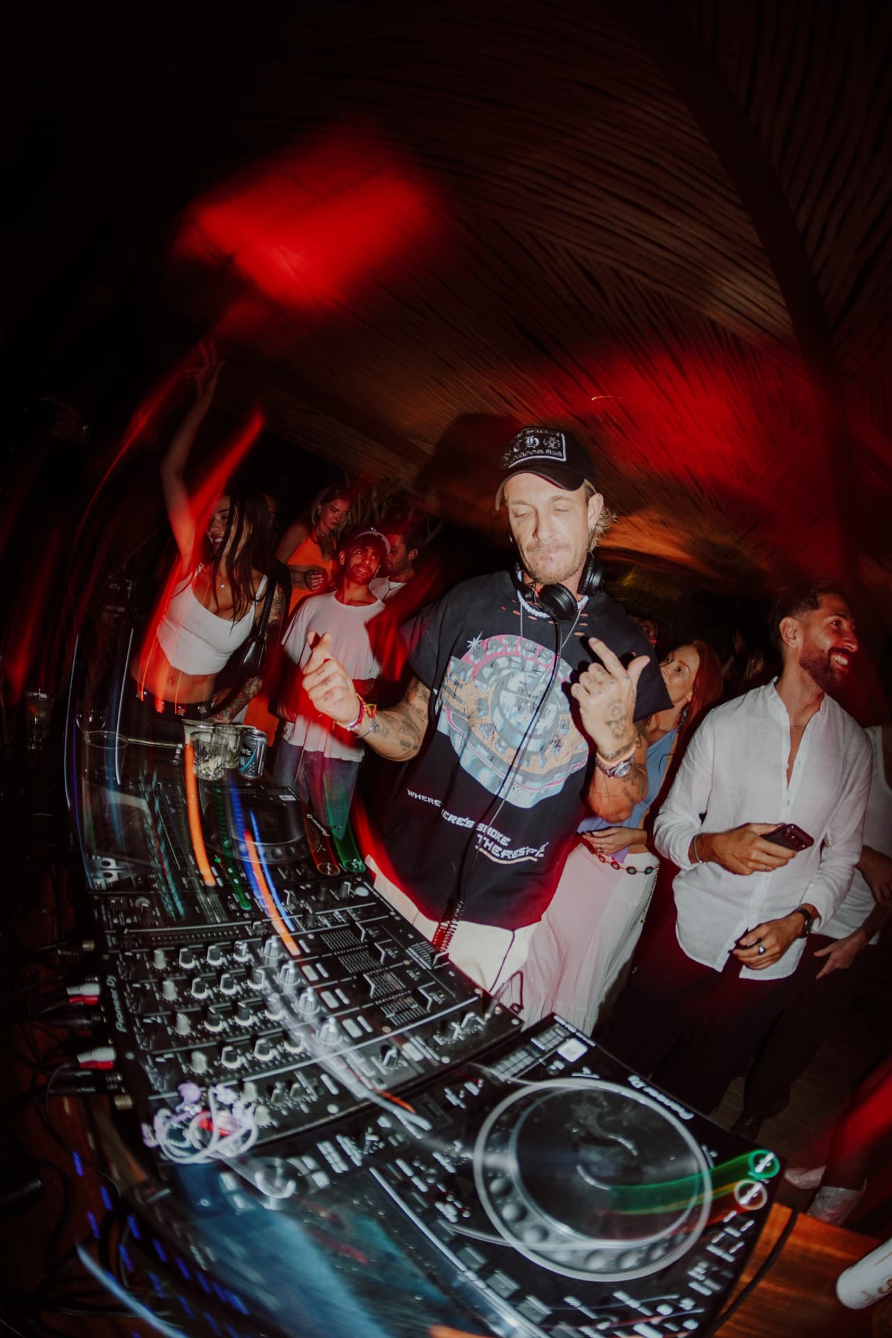 DJ playing to a packed dance floor under red light at The Garden Party