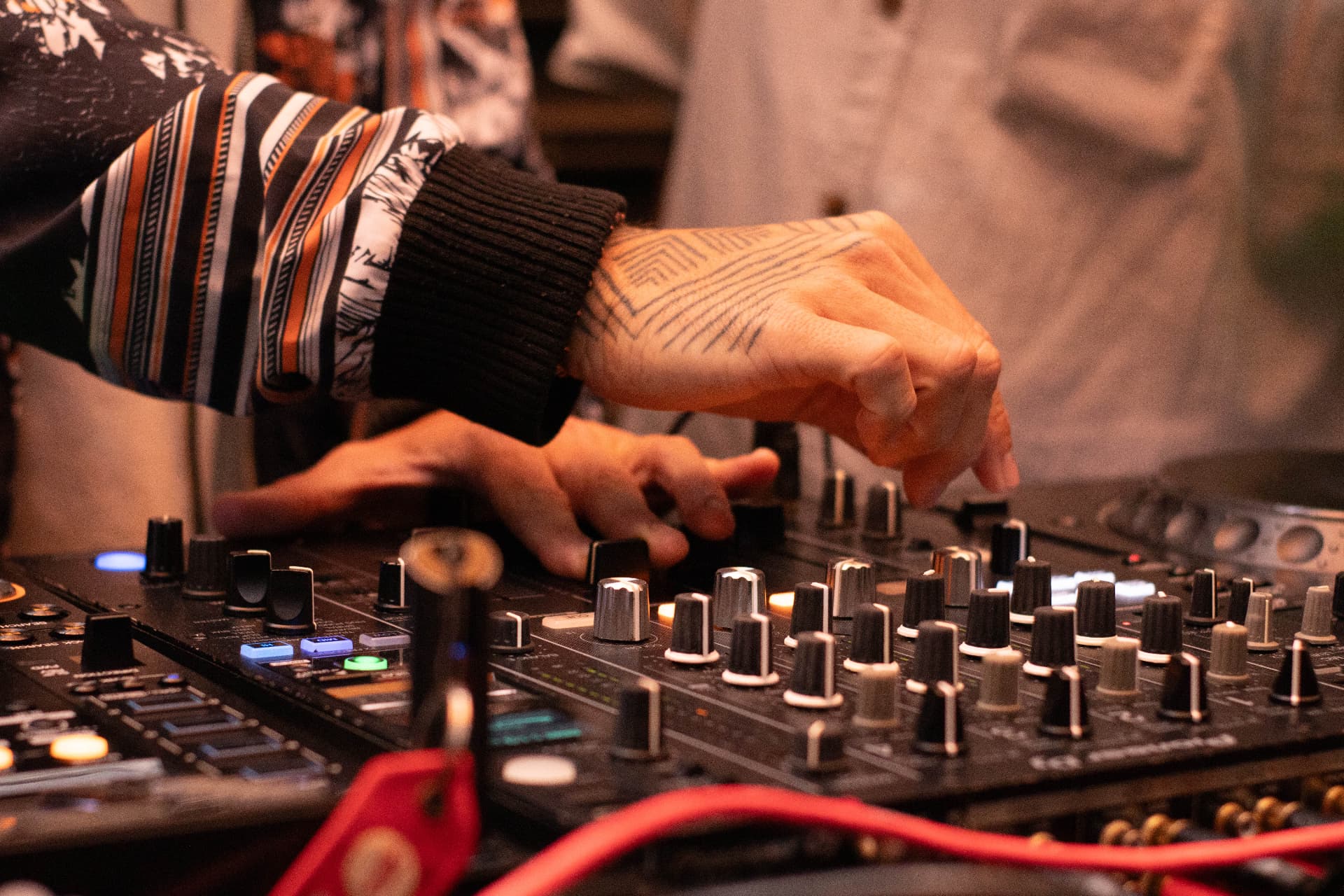 Tattooed hands on the mixer during a CALLORE set