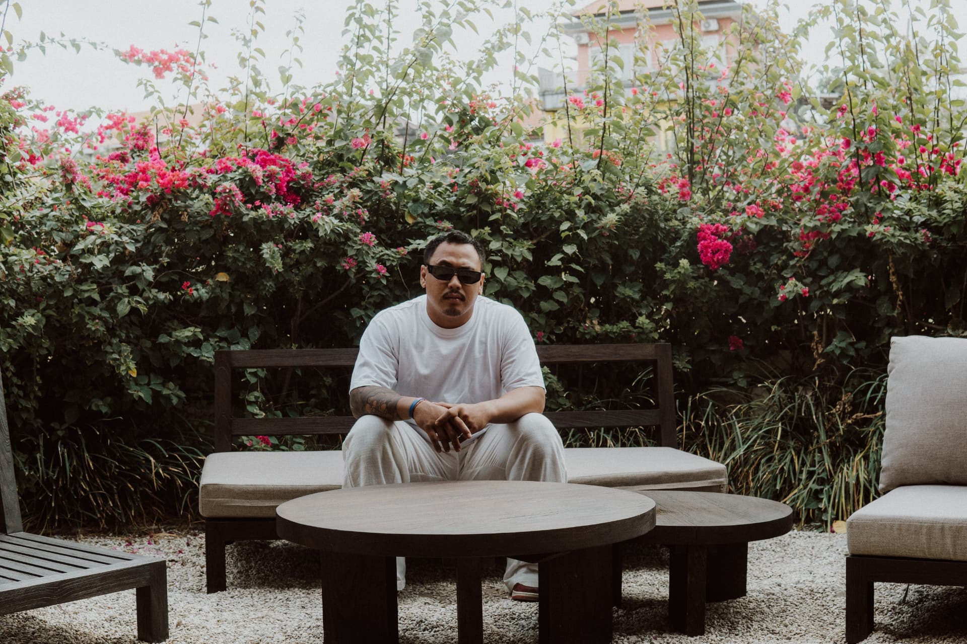 A founder of TAMAN seated in the garden lounge among bougainvillea