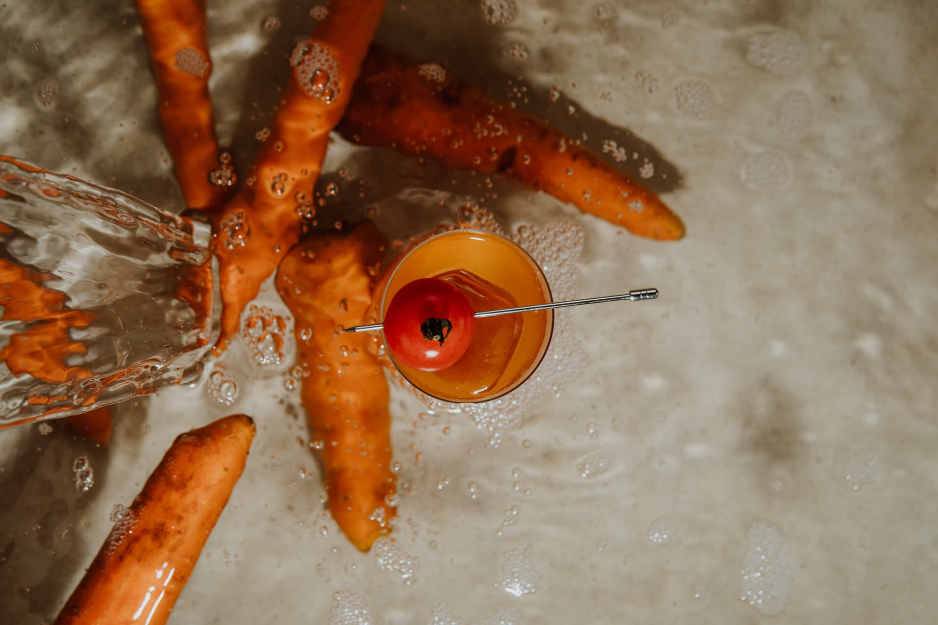 Tomato cocktail among fresh carrots and splashing water at TAMAN