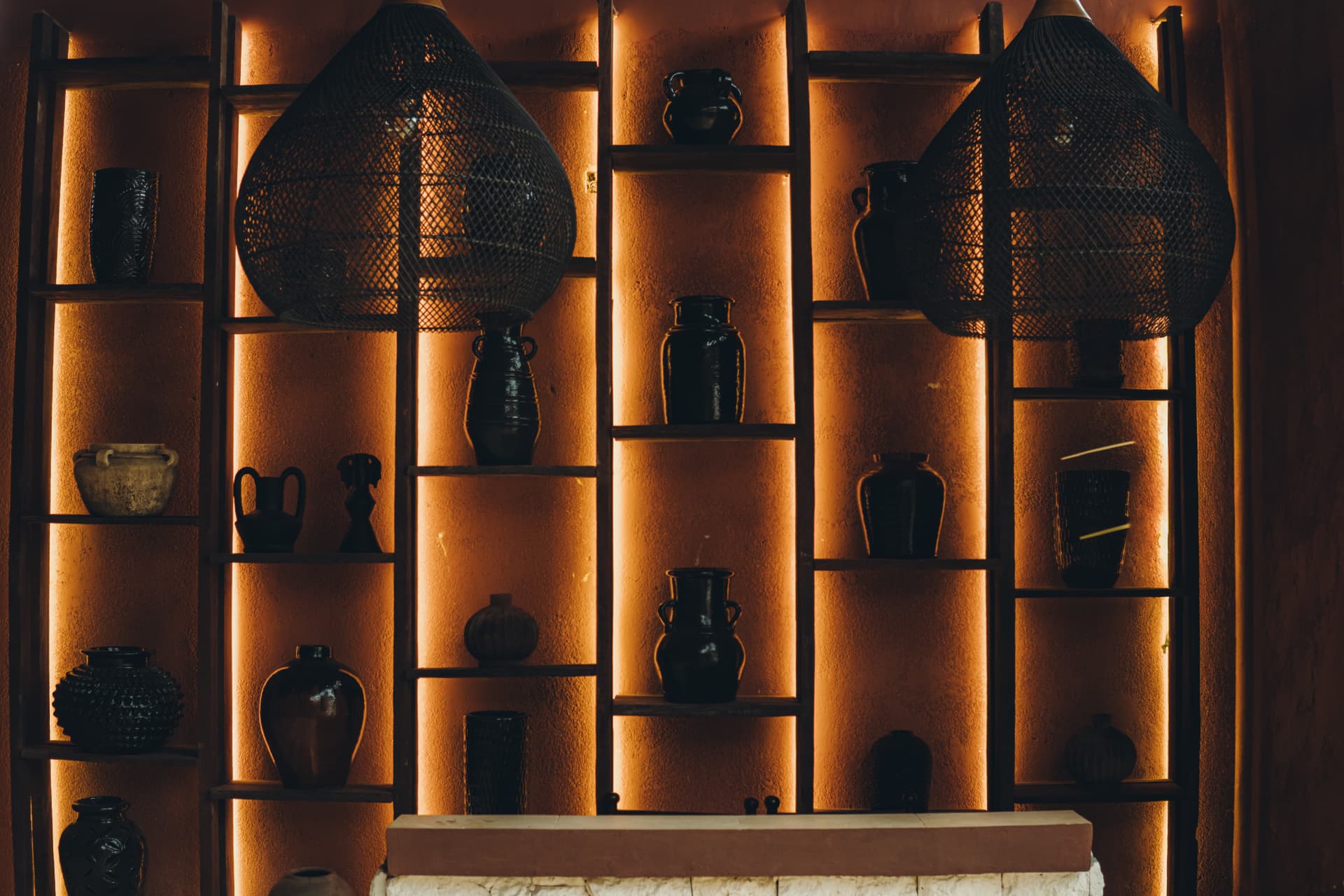 Warm terracotta interior shelves with woven pendant lights at TAMAN