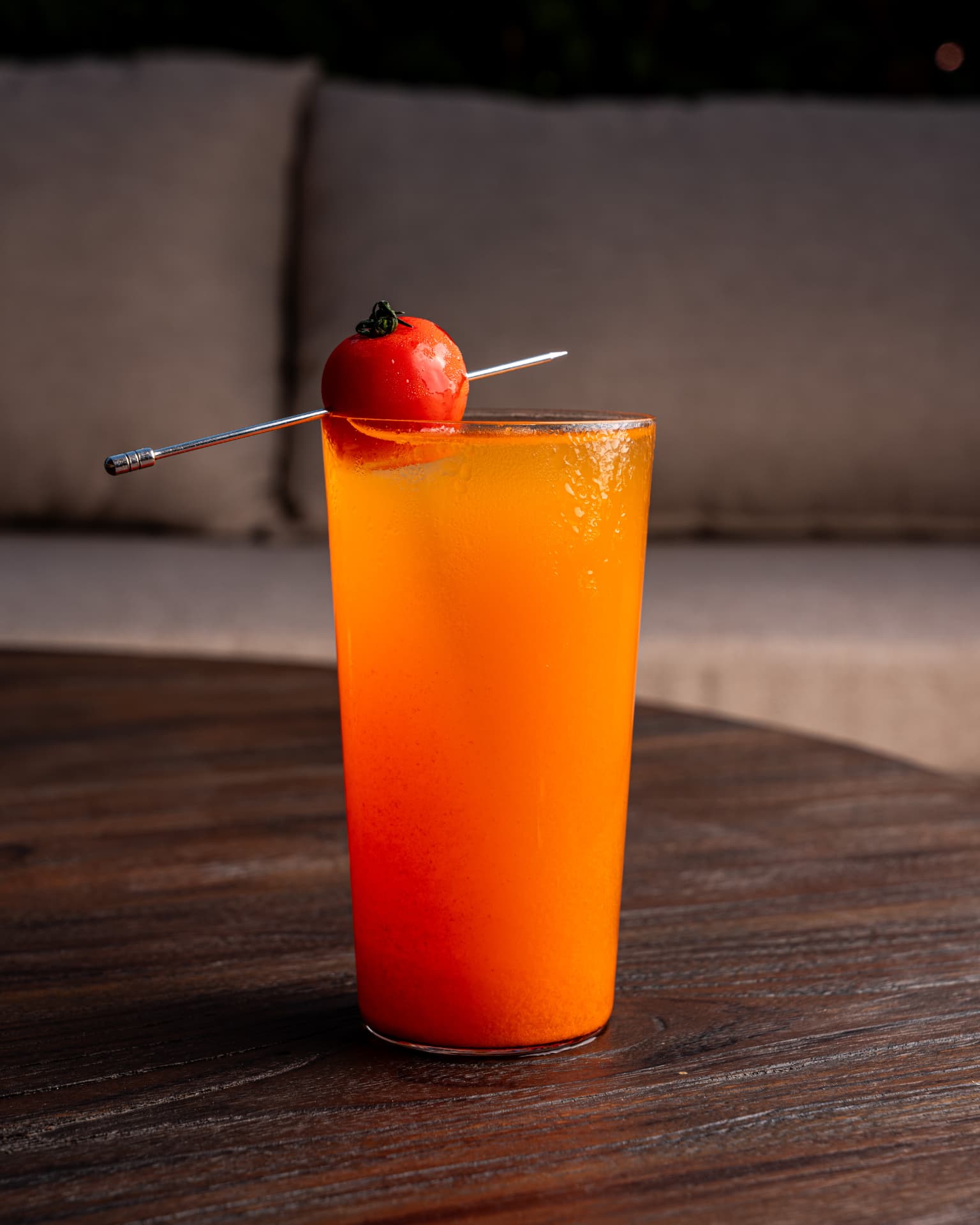 Bright tomato cocktail on a dark wooden table at TAMAN