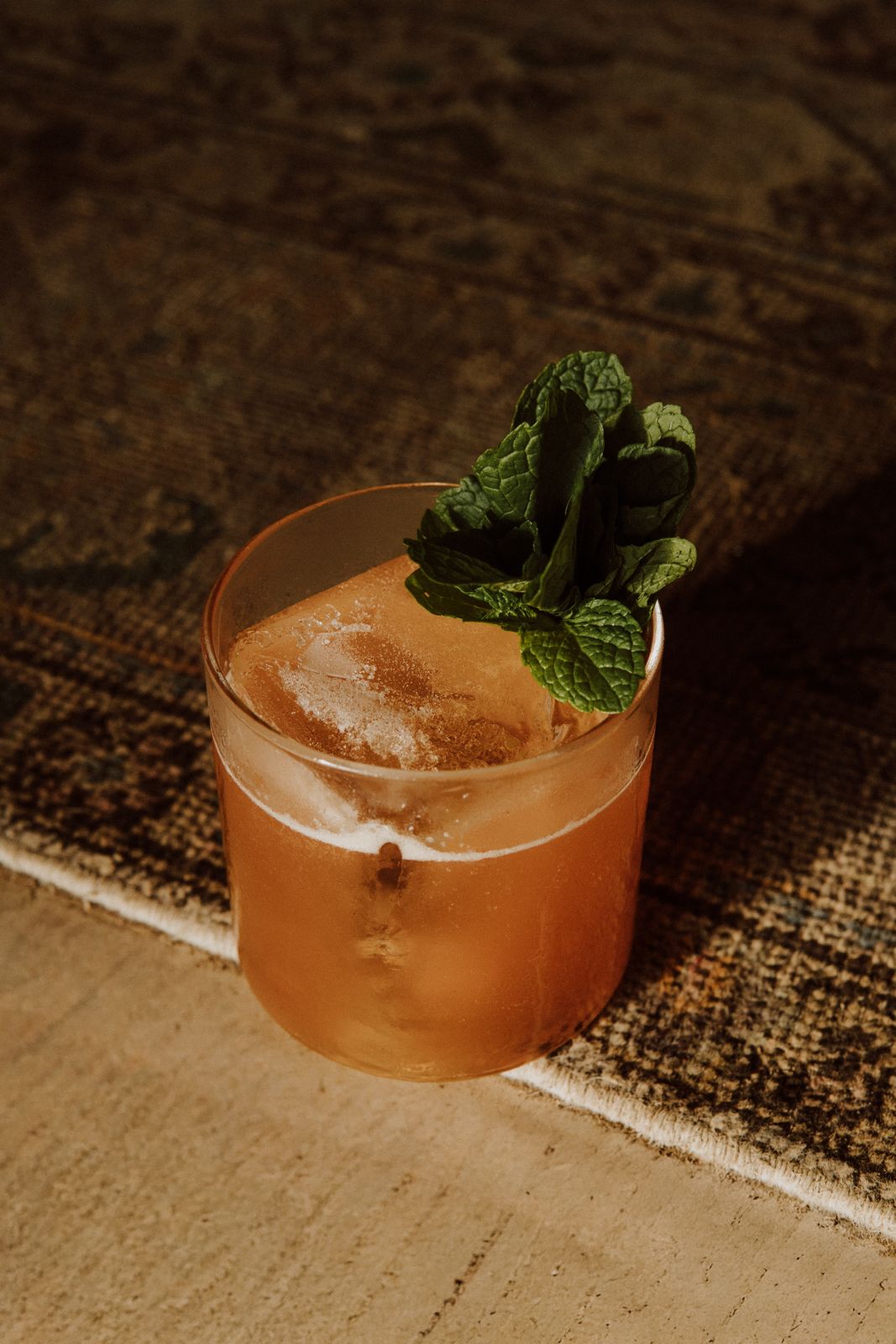 Amber cocktail over ice garnished with fresh mint at TAMAN